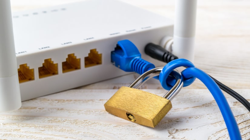 A white modem with a padlock tied around a blue ethernet cable to symbolise a locked modem.