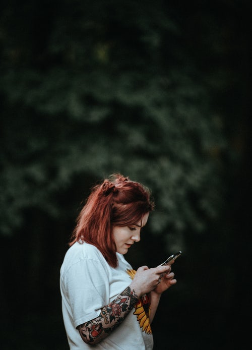 woman with tattoos on phone